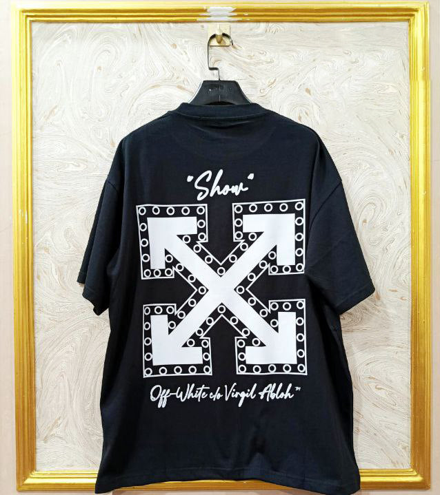 Black t-shirt with "Off-White™" design on a hanger against a decorative wall.