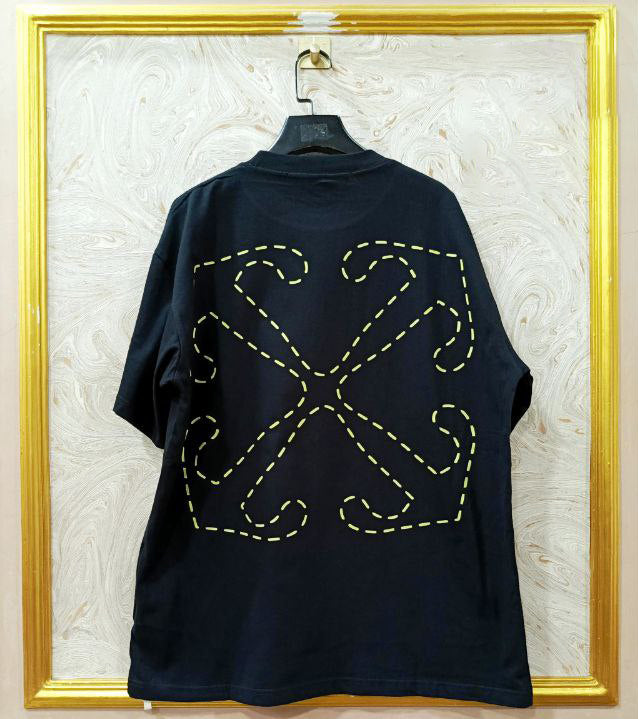 Black t-shirt with "Off-White™" design on a hanger against a decorative wall.