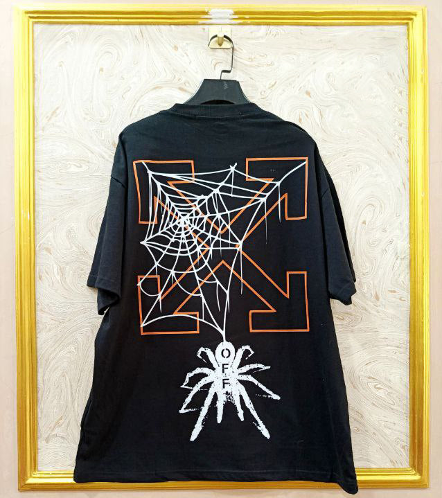 Black t-shirt with "Off-White™" design on a hanger against a decorative wall.