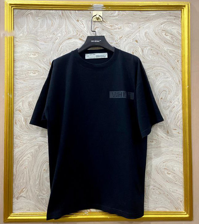 Black t-shirt with "Off-White™" logo on a hanger against a marble wall.