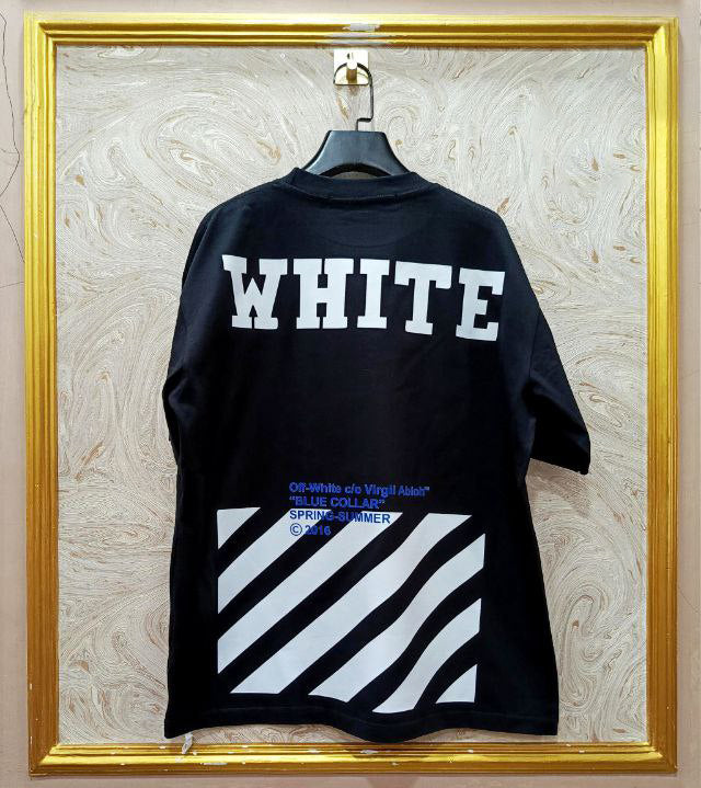 Black t-shirt with "Off-White™" design on a hanger against a decorative wall.