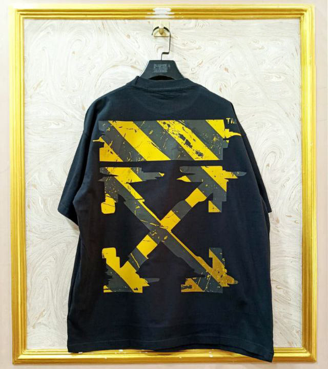 Black t-shirt with "Off-White™" design on a hanger against a decorative wall.