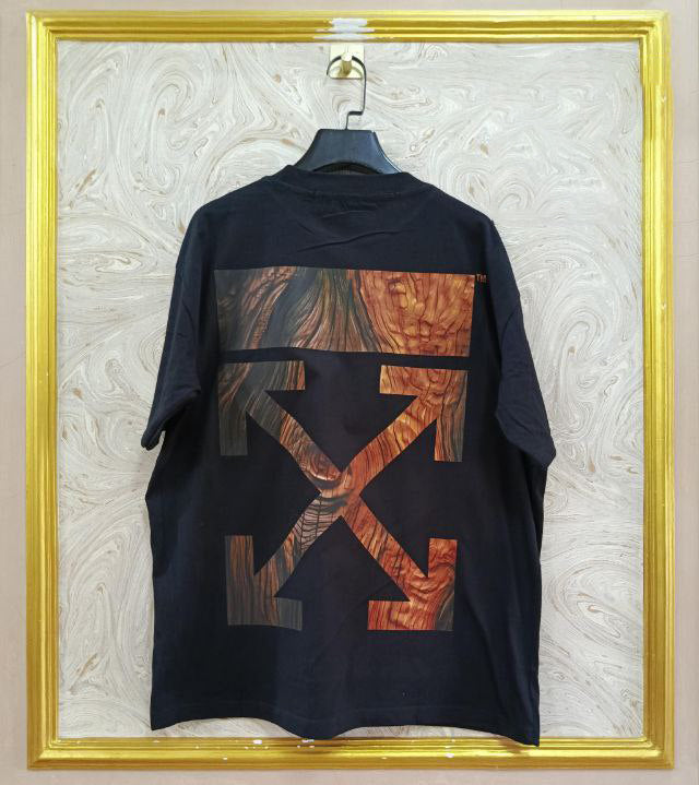 Black t-shirt with "Off-White™" design on a hanger against a decorative wall.