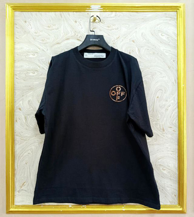 Black t-shirt with "Off-White™" logo on a hanger against a marble wall.