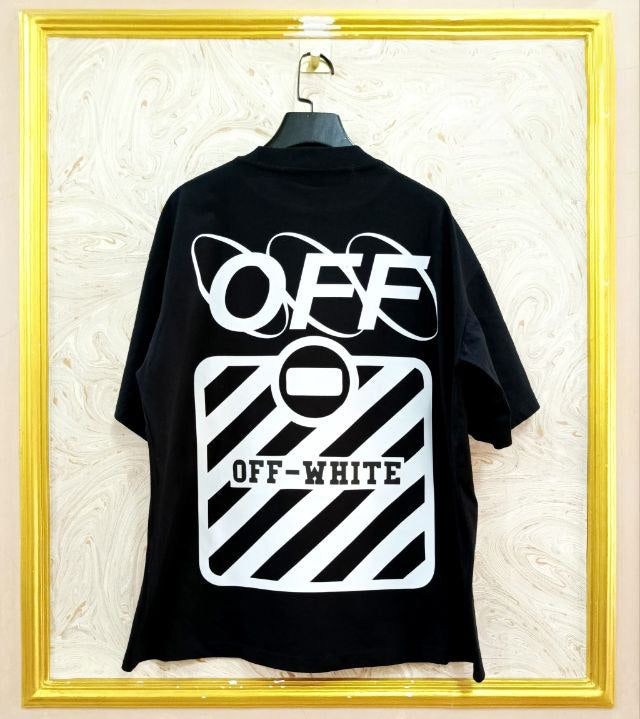 Black t-shirt with "Off-White™" design on a hanger against a decorative wall.