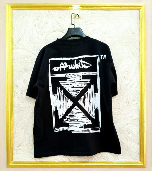 Black t-shirt with "Off-White™" design on a hanger against a decorative wall.