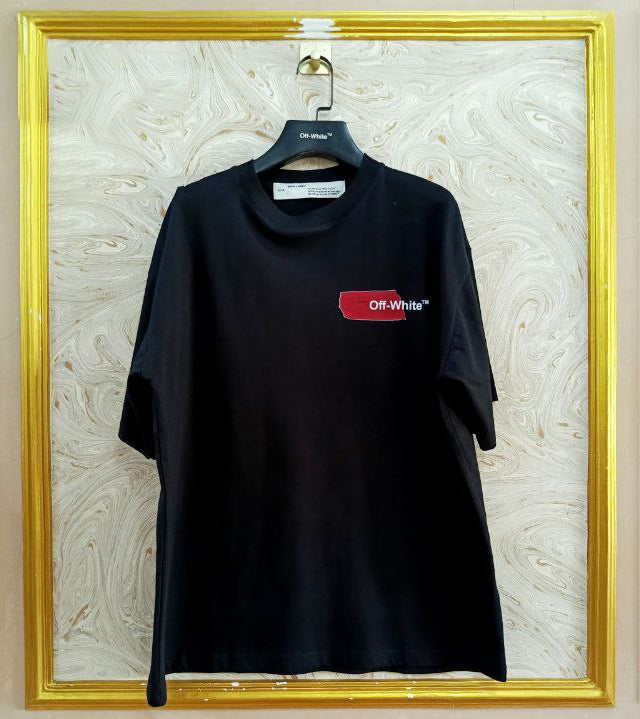 Black t-shirt with "Off-White™" logo on a hanger against a marble wall.