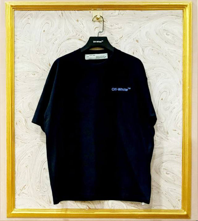 Black t-shirt with 'Off-White' logo on a hanger against a textured white wall.