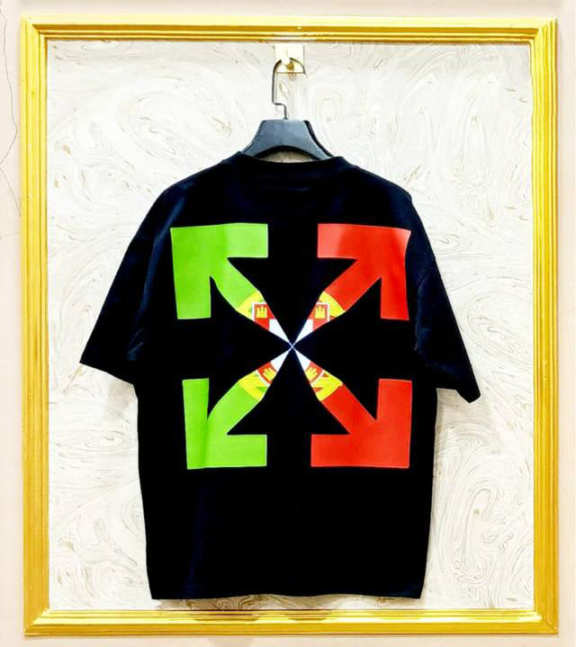 Black t-shirt with colorful arrow design on a hanger against a textured wall.