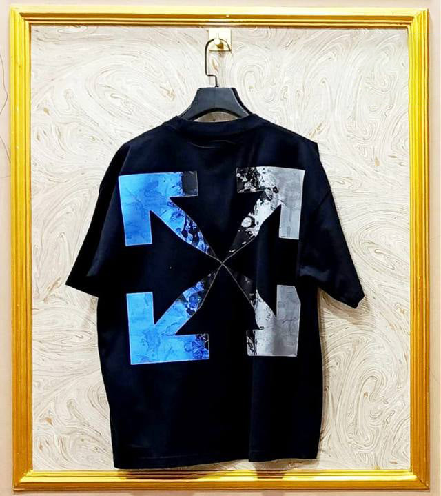 Black t-shirt with "Off-White™" design on a hanger against a decorative wall.
