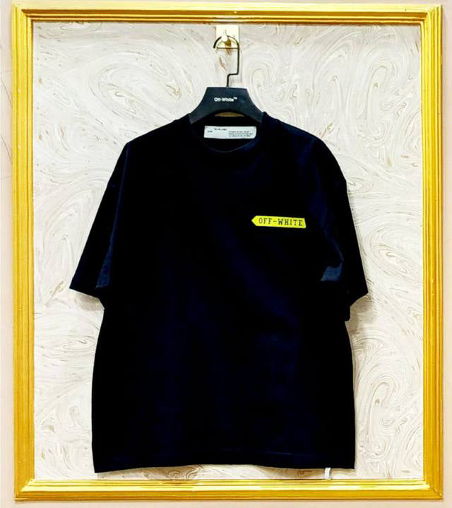 Black t-shirt with "Off-White™" logo on a hanger against a marble wall.