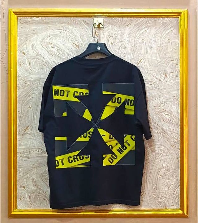 Black t-shirt with "Off-White™" design on a hanger against a decorative wall.