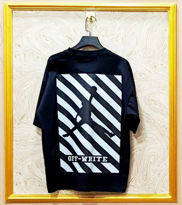 Black t-shirt with "Off-White™" design on a hanger against a decorative wall
