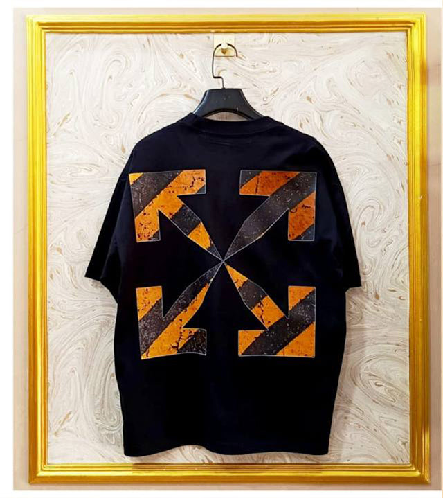 Black t-shirt with "Off-White™" design on a hanger against a decorative wall.