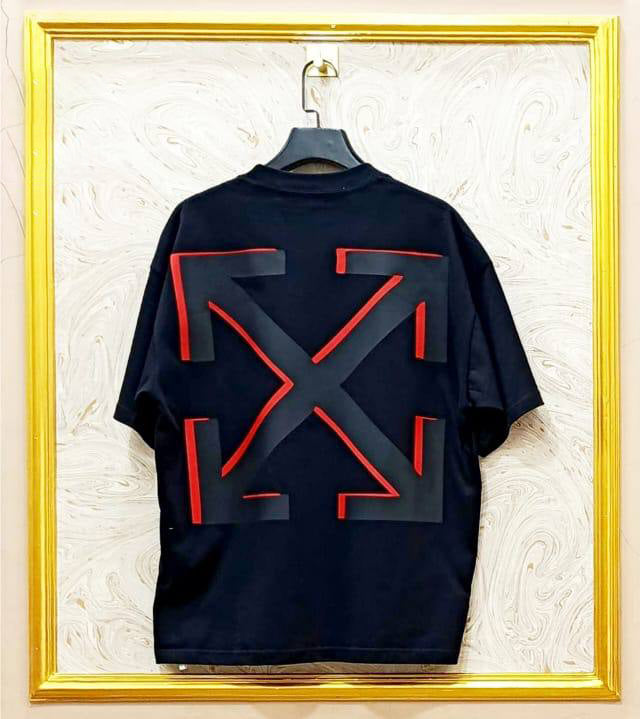 Black t-shirt with "Off-White™" design on a hanger against a decorative wall.