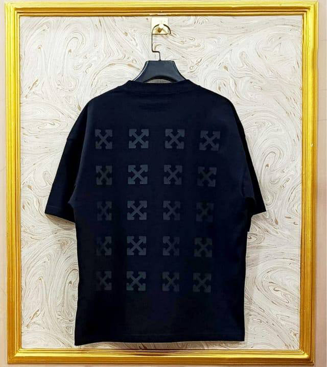 Black t-shirt with "Off-White™" design on a hanger against a decorative wall.