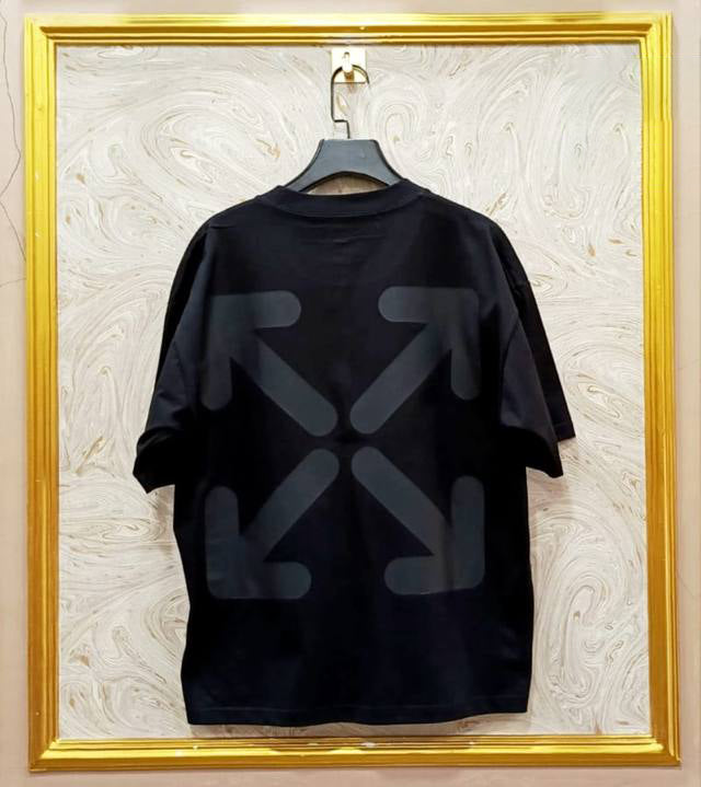 Black t-shirt with "Off-White™" design on a hanger against a decorative wall.
