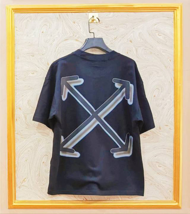 Black t-shirt with "Off-White™" design on a hanger against a decorative wall.