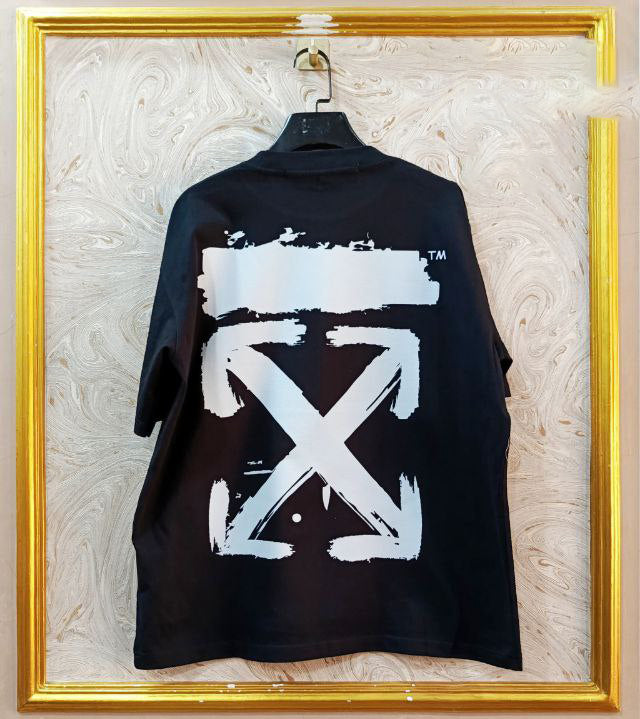Black t-shirt with "Off-White™" design on a hanger against a decorative wall.