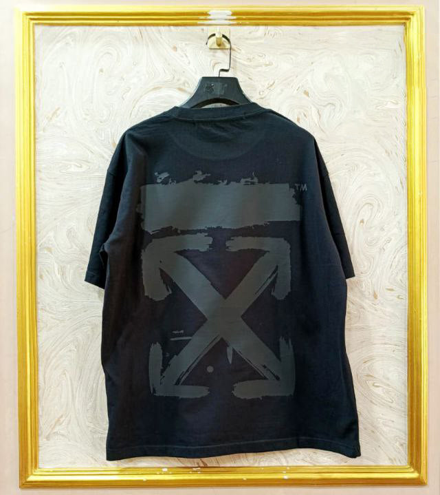 Black t-shirt with "Off-White™" design on a hanger against a decorative wall.