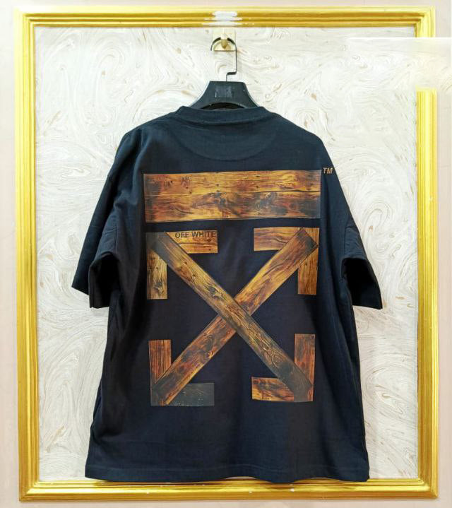 Black t-shirt with "Off-White™" design on a hanger against a decorative wall.