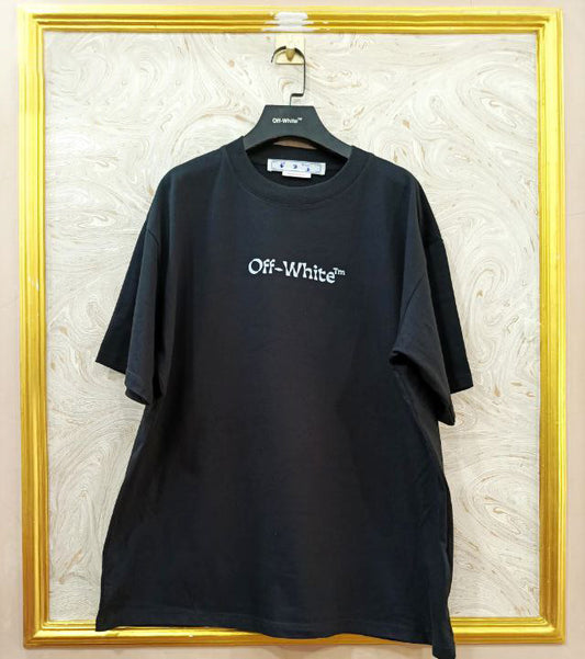 Black t-shirt with "Off-White™" logo on a hanger against a marble wall.