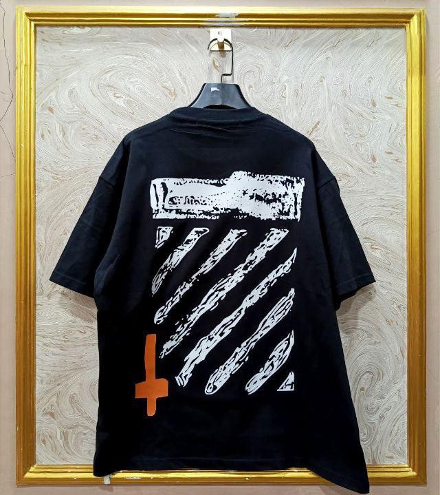 Black t-shirt with "Off-White™" design on a hanger against a decorative wall.