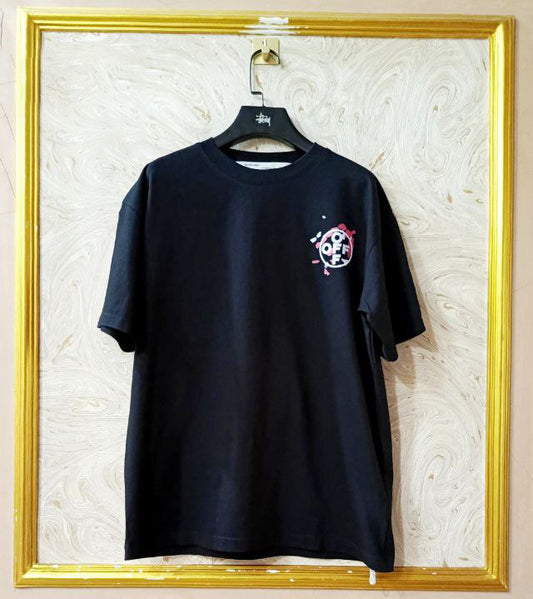 Black t-shirt with "Off-White™" logo on a hanger against a marble wall.