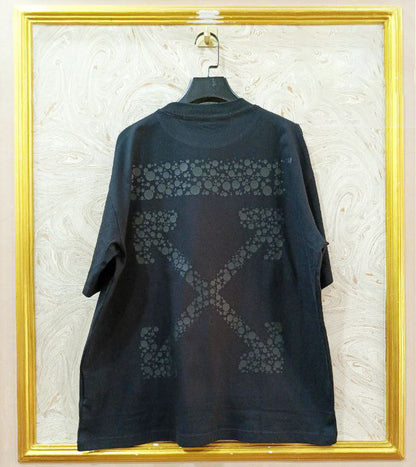 Black t-shirt with "Off-White™" design on a hanger against a decorative wall.