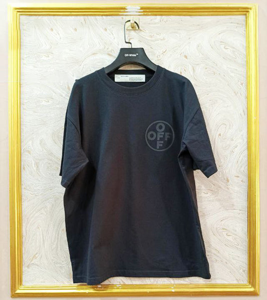 Black t-shirt with "Off-White™" logo on a hanger against a marble wall.