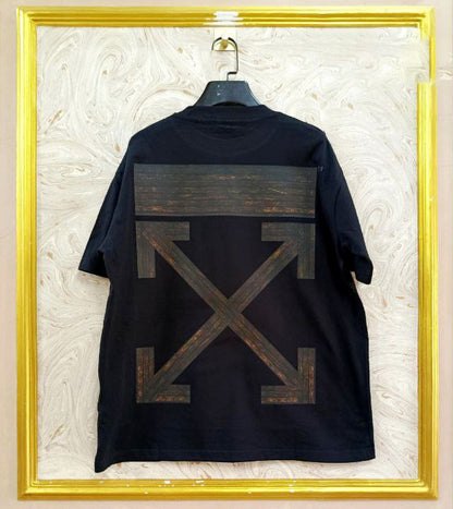 Black t-shirt with "Off-White™" design on a hanger against a decorative wall.