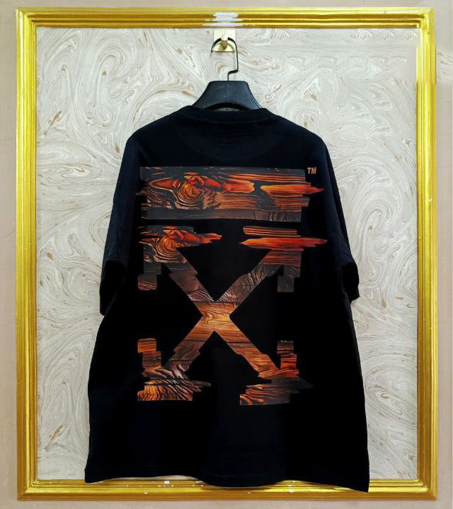 Black t-shirt with "Off-White™" design on a hanger against a decorative wall.