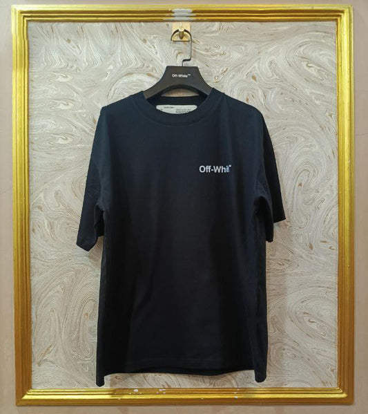 Black t-shirt with "Off-White™" design on a hanger against a decorative wall.
