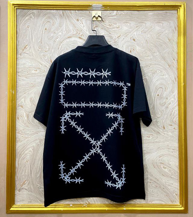 Black t-shirt with "Off-White™" design on a hanger against a decorative wall.