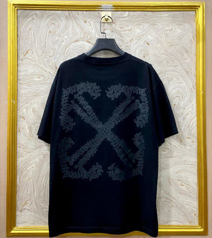 Black t-shirt with "Off-White™" design on a hanger against a decorative wall.