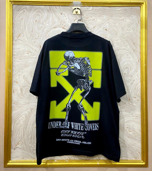 Black t-shirt with "Off-White™" design on a hanger against a decorative wall.