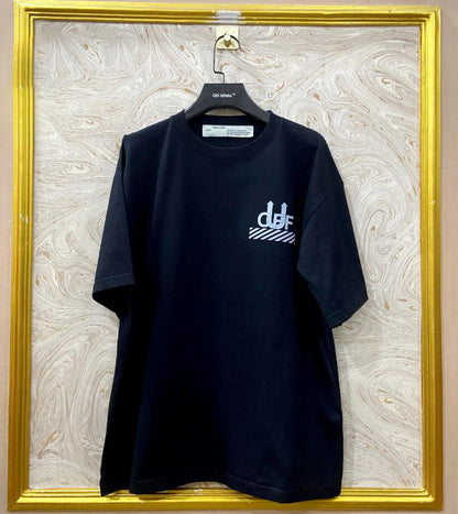 Black t-shirt with "Off-White™" logo on a hanger against a marble wall.