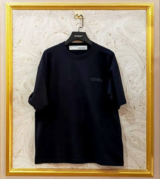 Black t-shirt with a brand logo on a hanger against a marble wall.
