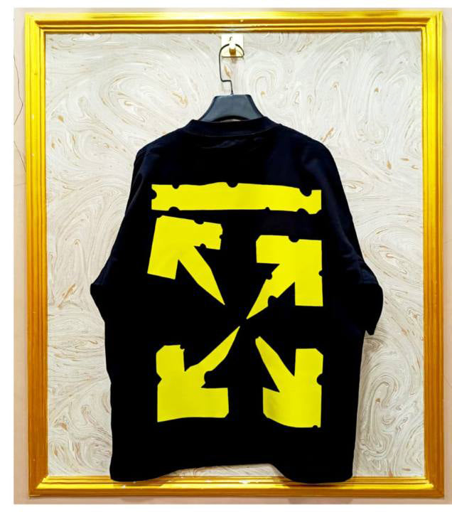 Black sweatshirt with yellow graphics on a hanger against a textured wall.
