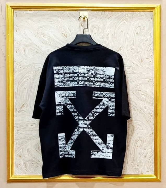 Black t-shirt with white geometric "Off-White™" design on a hanger against a decorative wall.