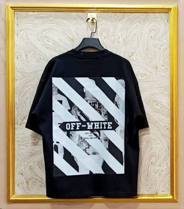 Black t-shirt with white graphic design on a hanger against a marble wall.