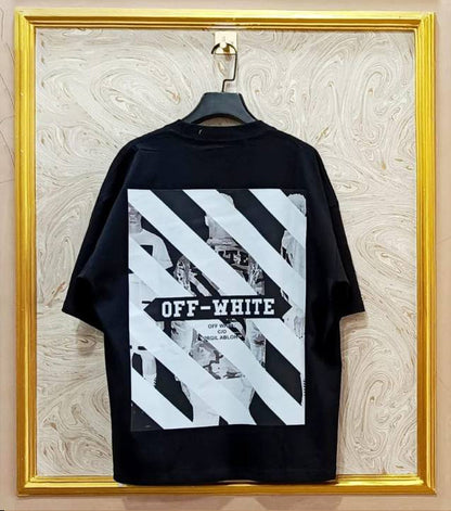Black t-shirt with white graphic design on a hanger against a marble wall.