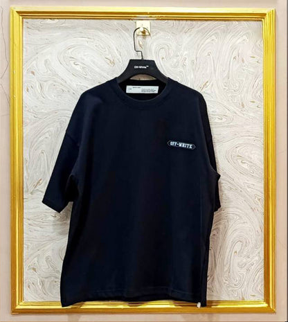 Black t-shirt with white "Off-White™" logo on a hanger against a marble wall.