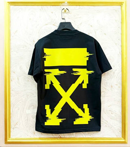Black t-shirt with yellow graphic design on a hanger against a textured white wall.