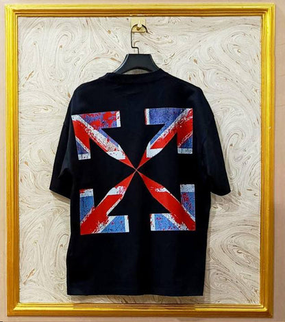 Black t-shirt with red, white, and blue geometric design on a hanger against a marble wall.