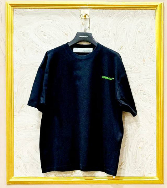 Black t-shirt with a green 'Off-White™' logo on a hanger against a textured white wall.