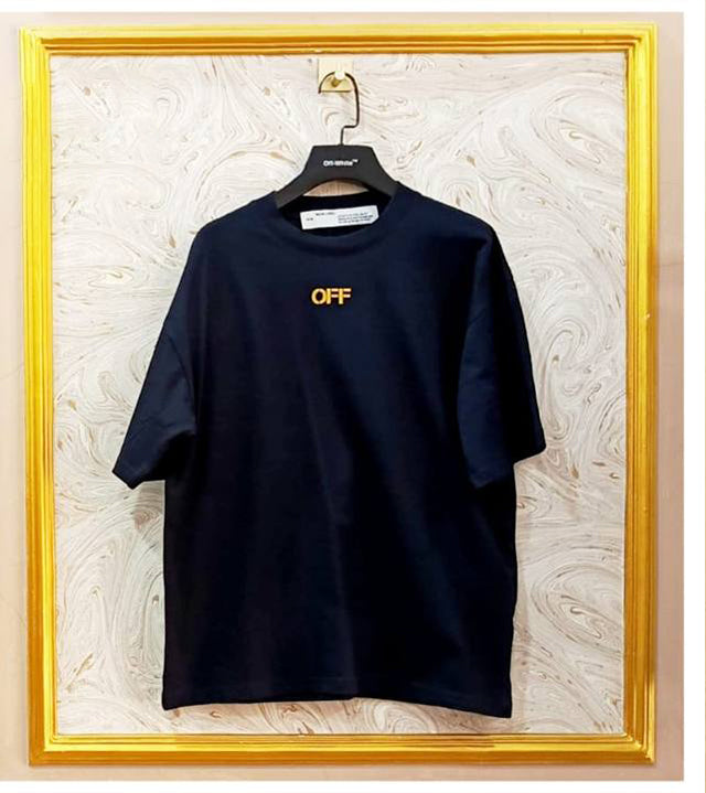 Black t-shirt with "Off-White™" logo on a hanger against a marble wall.