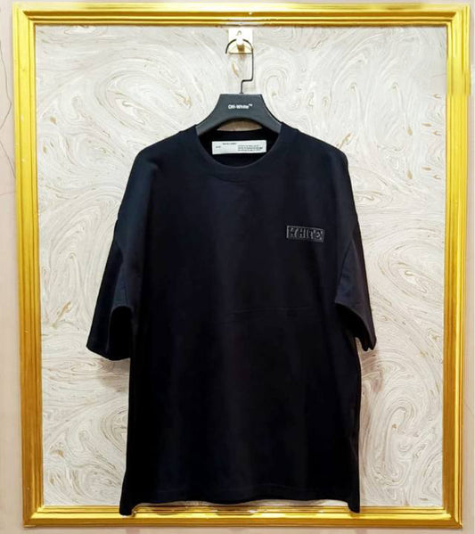Black t-shirt with "Off-White™" logo on a hanger against a marble wall.