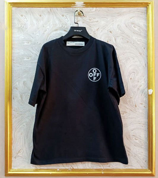Black t-shirt with "Off-White™" logo on a hanger against a marble wall.